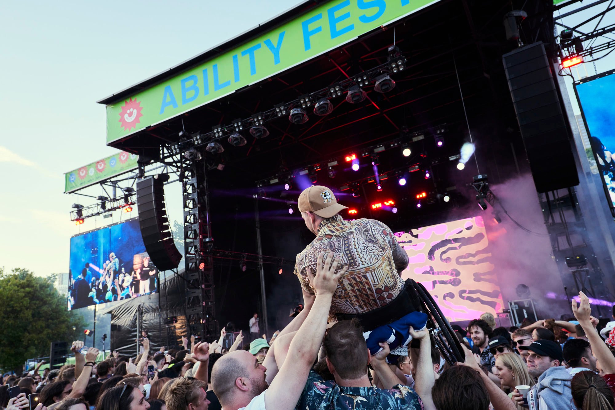 A person in a wheelchair crowd surfing at Ability Fest. 