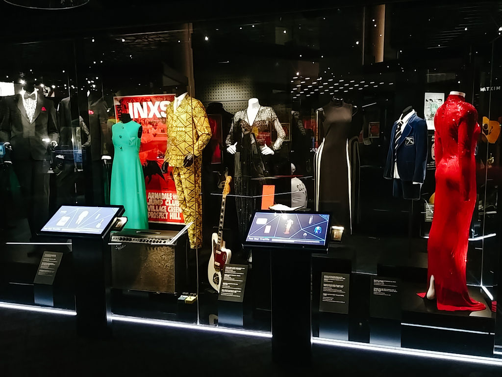 The Two-Way Traffic exhibition at the Australian Music Vault, highlighting dresses and suits worn by Australian musicians are behind glass displays. 