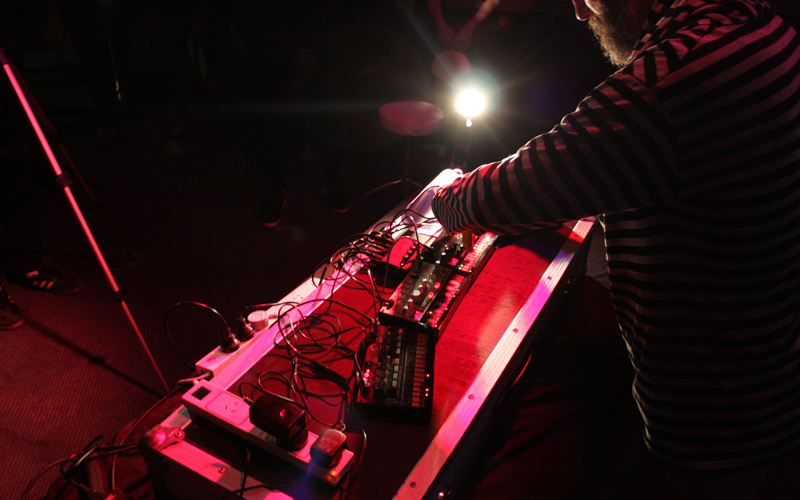A person standing over desk with sound control equipment. A light is shining on his face. 
