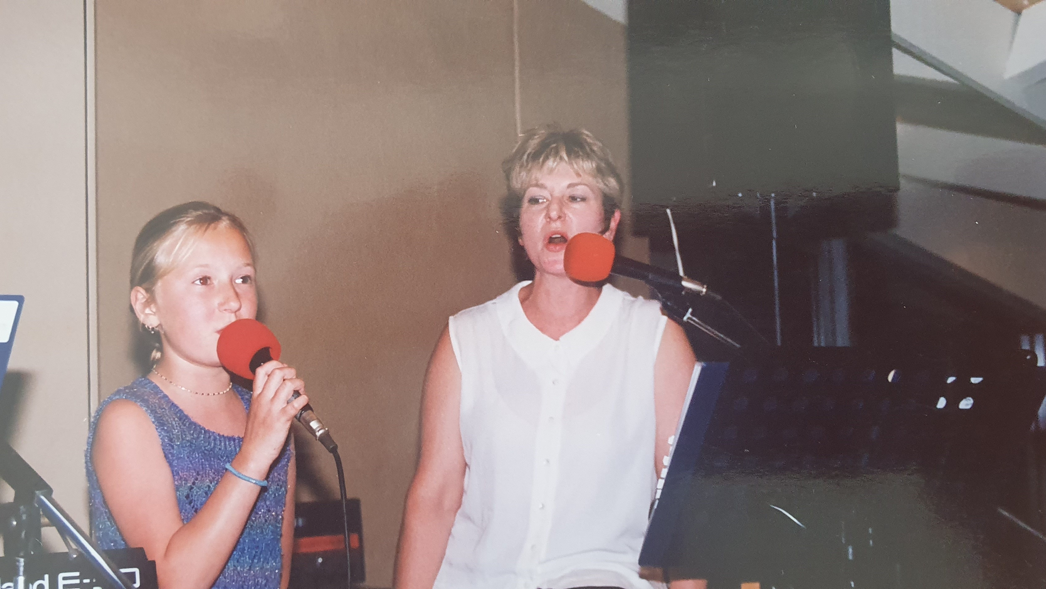 A child and a woman are singing together into microphones