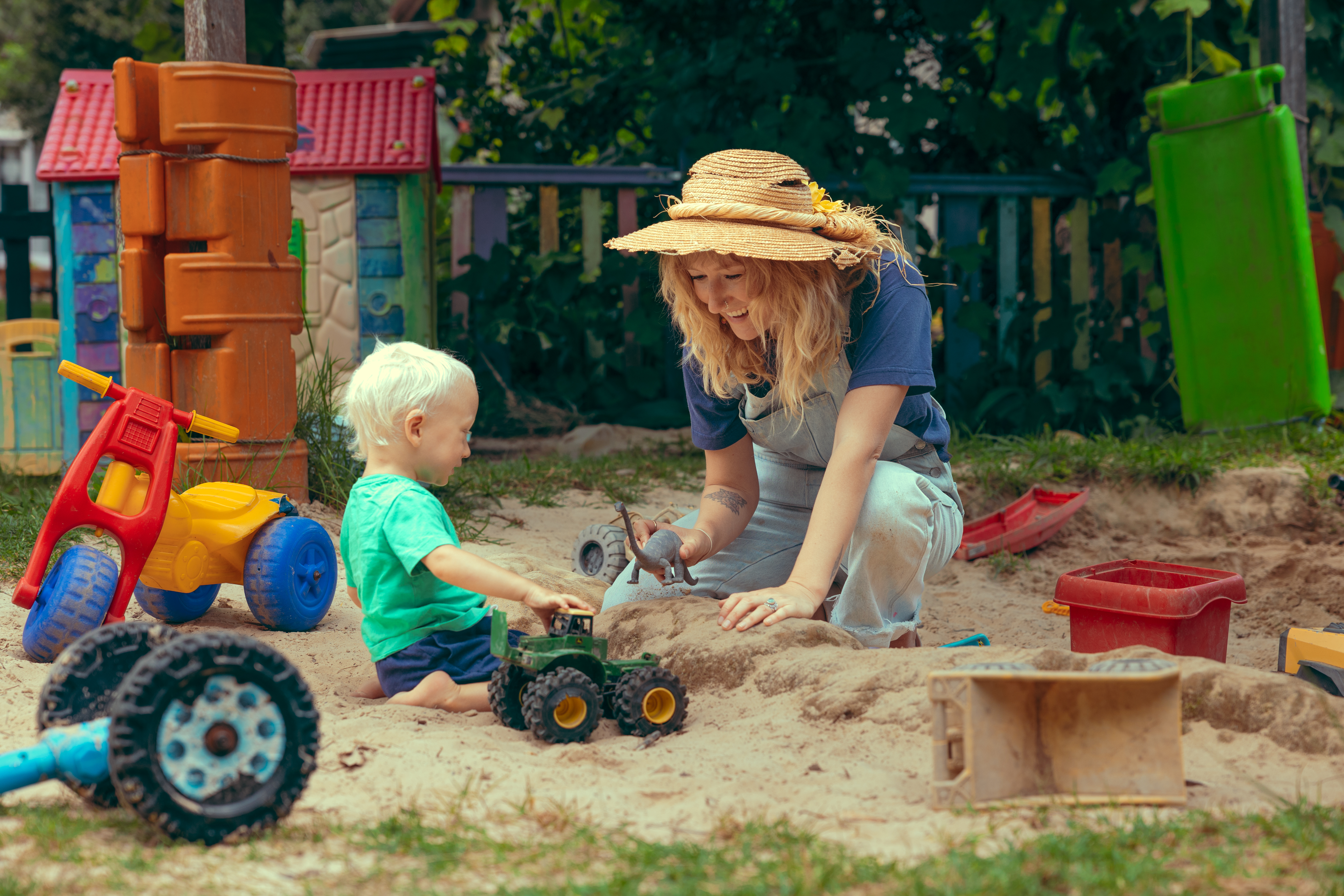 Alana Wilkinson and her young child Raffy playing in a sand pit with toy trucks.