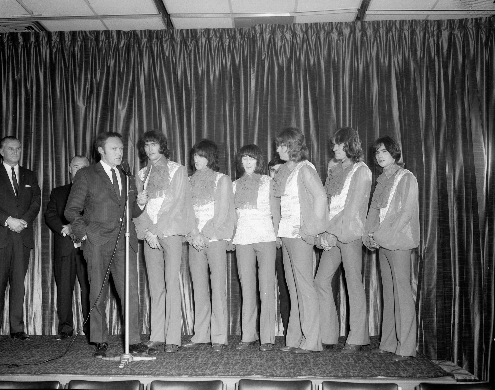 The Valentines (band) Backstage At Hoadley’s Battle Of The Bands. Black and white image. The band are all wearing frilly shirts and are standing in front of a curtain backdrop. Photograph By Laurie Richards.