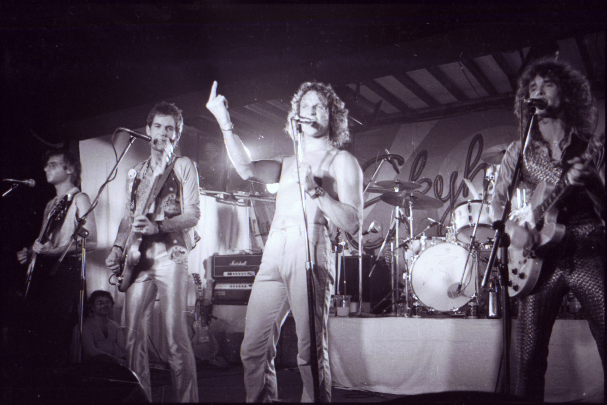 Black and white image of Skyhooks (band) performing on stage. Photograph By Kathleen O’Brien.
